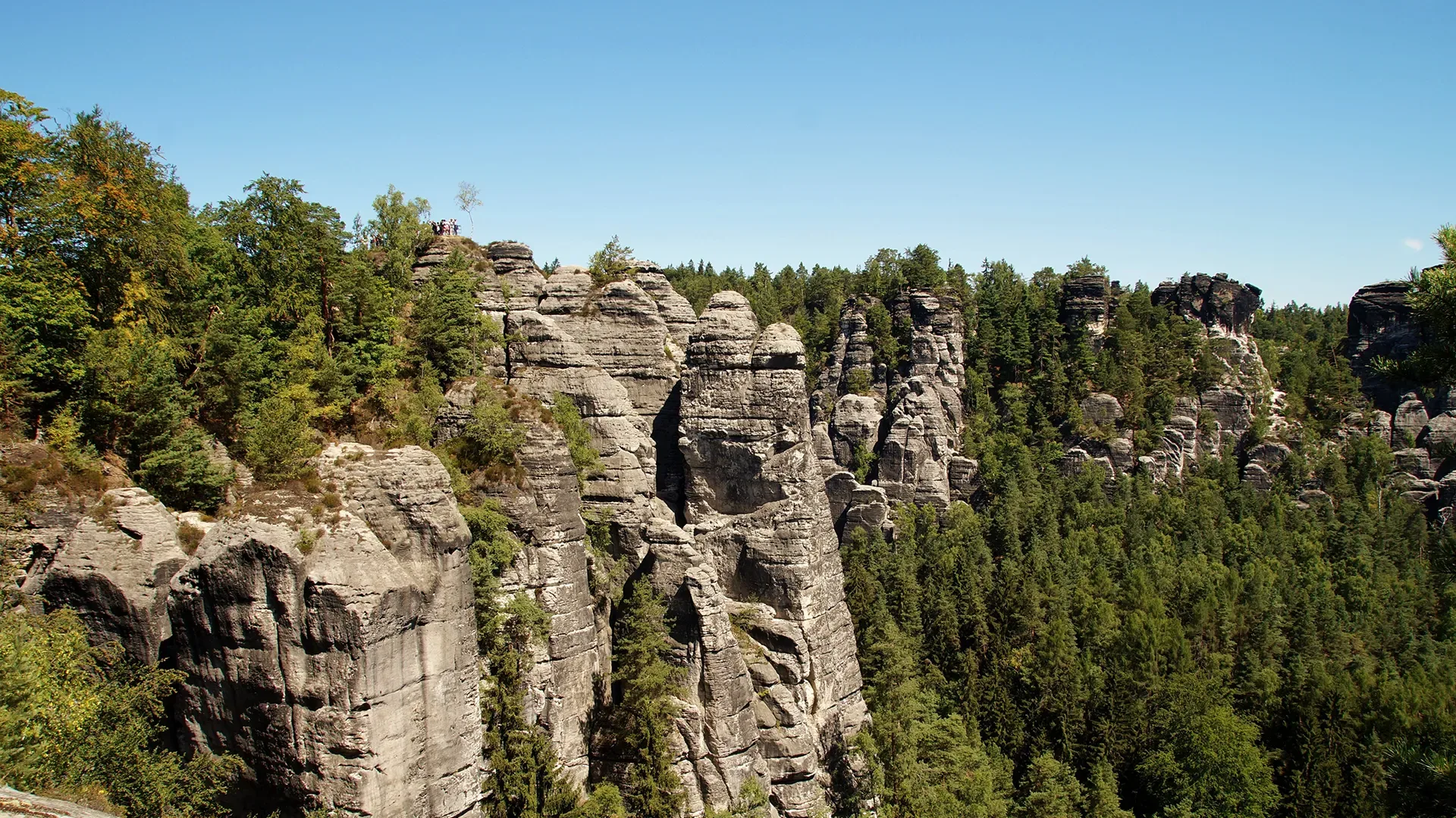 Felsformationen mit steilen Klippen und bewaldeten Hängen unter blauem Himmel