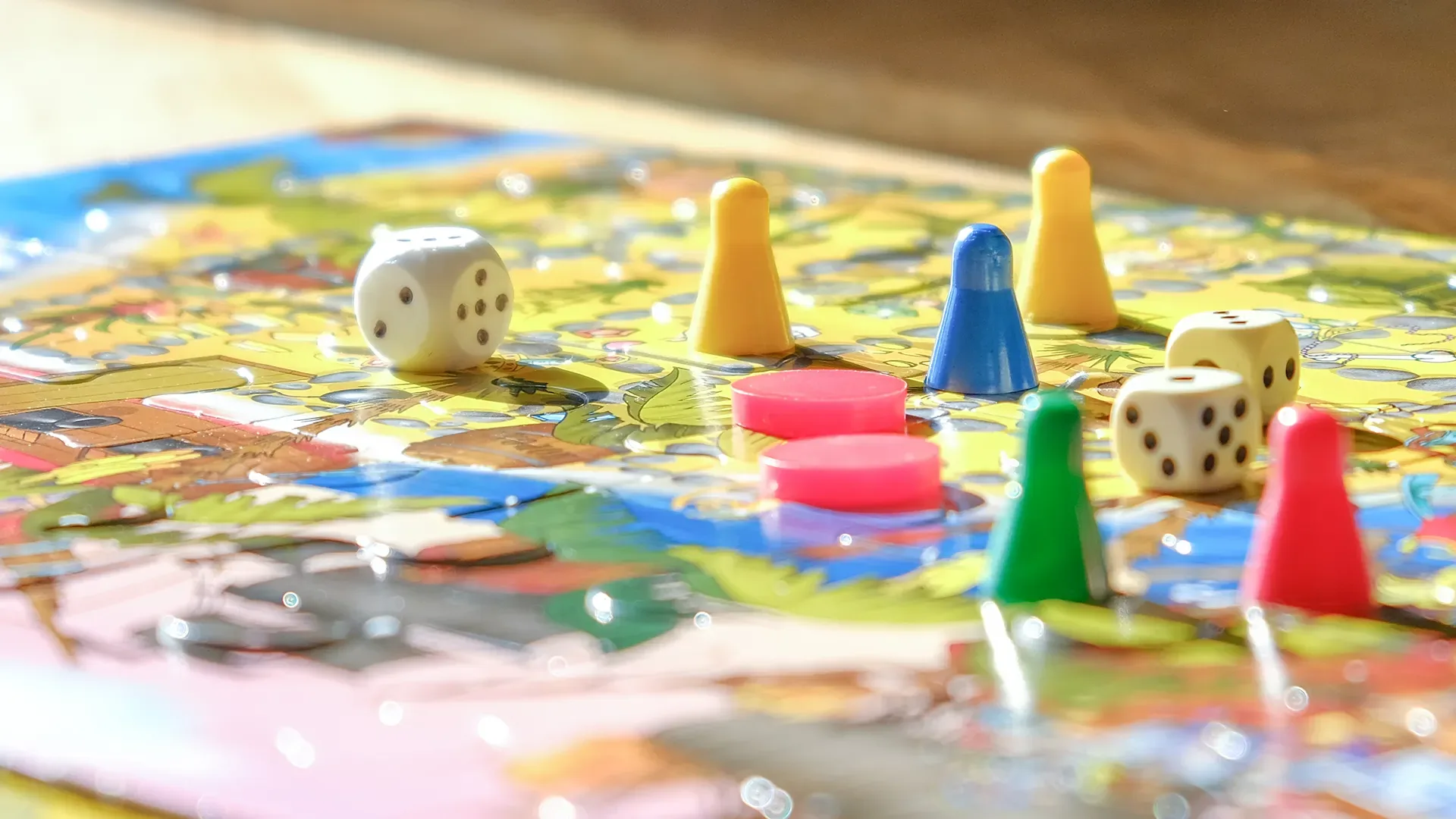 Brettspiel mit bunten Spielfiguren, Spielsteinen und Würfeln auf einem Spielplan
