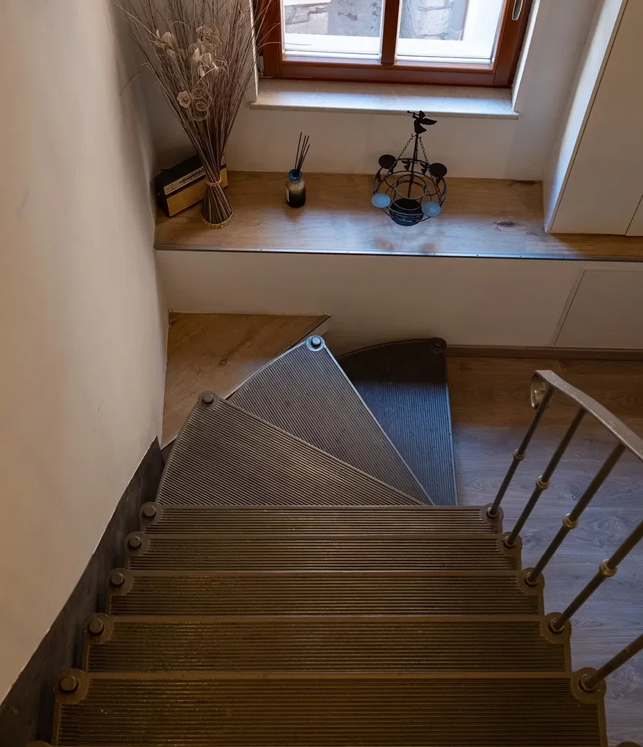 Holztreppe mit grauen Stufen und Metallgeländer neben Fensterbank mit Dekoobjekten