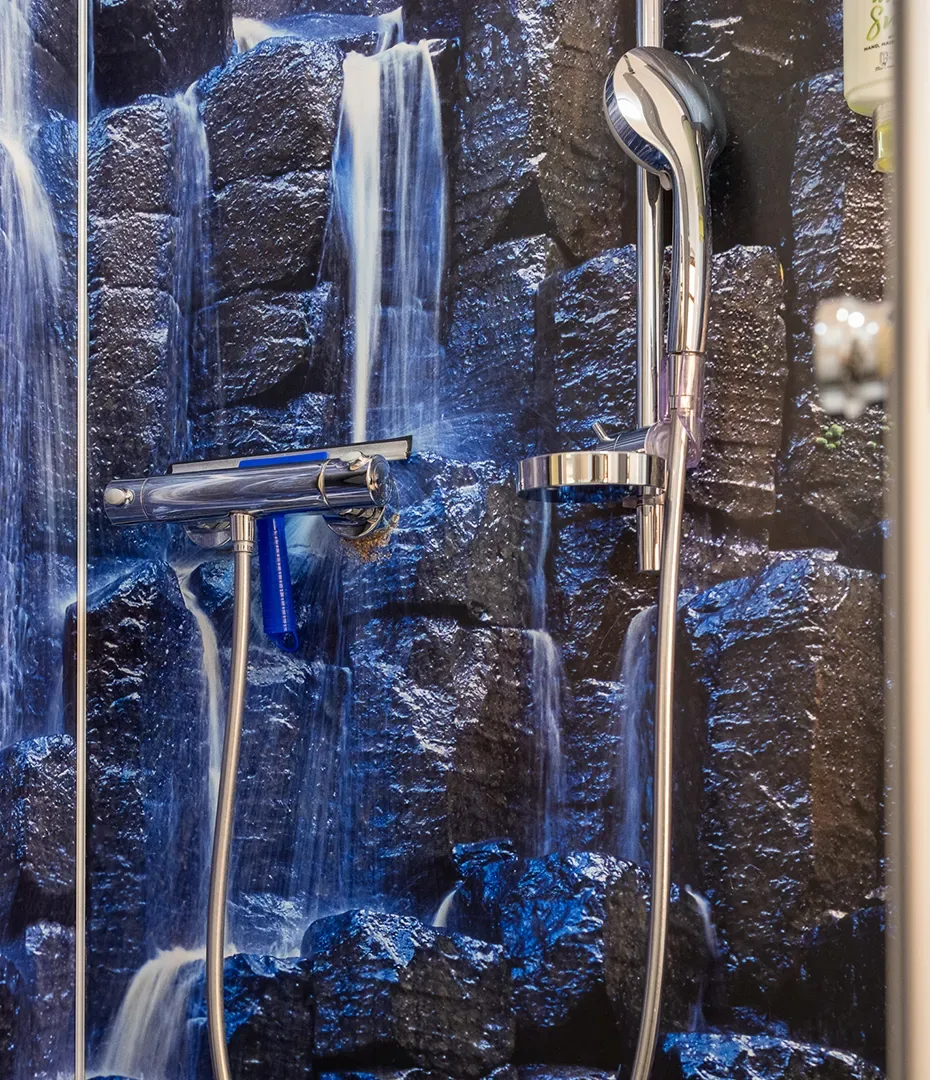 Duscharmatur mit Handbrause vor einer Wand mit Wasserfallmotiv