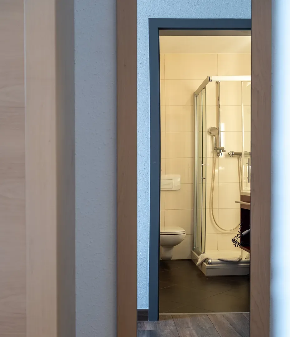 Blick durch eine Tür in ein Badezimmer mit Duschkabine und Toilette